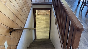 A wooden staircase leading to a second-floor balcony with a stone fireplace.