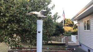 A metal sign with 'Cape Rogue' written on it, mounted on a white pole with a bird figure on top.