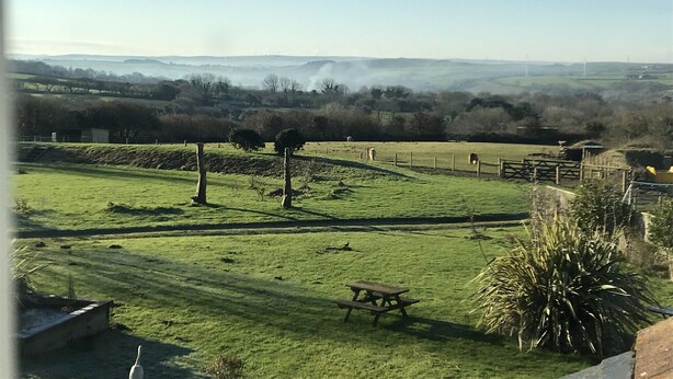 A rural landscape with a grassy field, a wooden picnic table, and a stone wall. - Pool Lodge, rural cottage-house, self catering property, rural, North Cornwall. (Helstone)