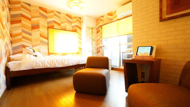 A hotel room with a bed, two ottomans, a desk with a computer, and a window with blinds. - A-Tomato Takayama Station (高山市)