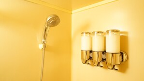 A bathroom with a chrome showerhead and three wall-mounted light fixtures. - A-Tomato Takayama Station (高山市)