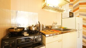 A compact kitchen with a stove, pots, a sink, and a microwave. - A-Tomato Takayama Station (高山市)