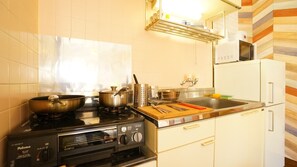 Une cuisine de taille réduite équipée d’une cuisinière, de casseroles, d’un évier et d’un four à micro-ondes.