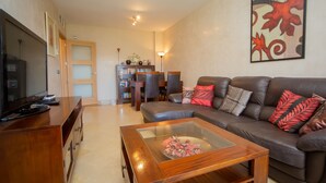 Una sala de estar con un sofá de cuero, una mesa de centro, un televisor y una estantería.