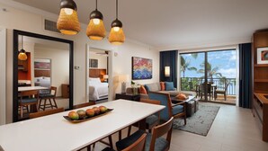Ein modernes Hotelzimmer mit Essbereich, einer Couch und einem Balkon mit Blick auf Palmen.