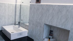 Ein Badezimmer mit weißem Waschbecken, schwarzer Arbeitsplatte und Marmorfliesen.