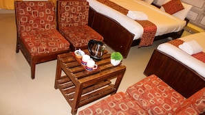 Ein Hotelzimmer mit zwei Einzelbetten, einem Holztischchen mit Tablett und Tassen sowie gemusterten Sofas.