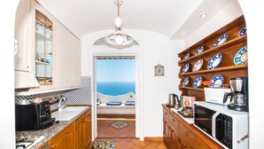 A compact kitchen with a view of the sea, a coffee machine, and a microwave. - CASA PERLA - Positano AMALFI COAST (Positano)