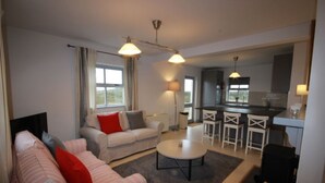 A modern living room with a sofa, a dining table, and a kitchen area. - No 8 Leitirshask, Ballyconneely - Full Of Country Living Chic. (Ballyconneely)