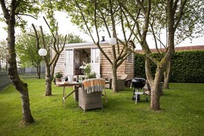Un espacio al aire libre acogedor con mesa, sillas y una parrilla.