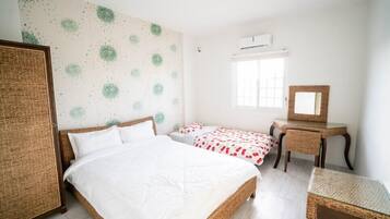 A bedroom with a large bed, two smaller beds, a desk, and a mirror.