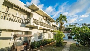 A multi-story building with balconies, a swing chair, and a small garden area. - Karis Villa (Saipan)