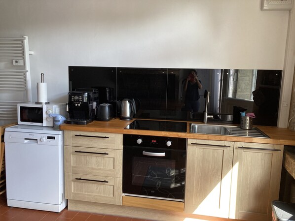 A compact kitchen with a microwave, coffee maker, toaster, kettle, and oven.