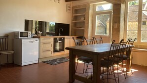 Una cocina con una mesa y sillas de madera, un microondas, horno y fregadero.