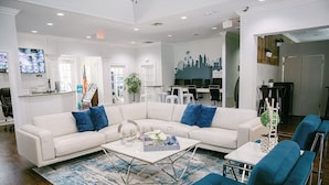 Een moderne woonkamer met een witte modulaire bank, blauwe kussens, een salontafel en blauwe fauteuils.