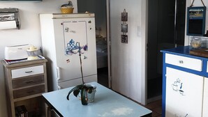 A compact kitchen with a refrigerator, a table, and a hanging light fixture. - Au Vieil, Small fisherman's house (Noirmoutier-en-l'Île)