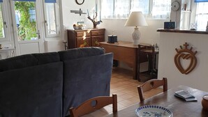 A cozy living room with a sofa, a wooden dining table with chairs, a lamp, and a decorative heart on the wall. - Au Vieil, Small fisherman's house (Noirmoutier-en-l'Île)