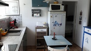A compact kitchen with a dining table, a refrigerator, and a microwave. - Au Vieil, Small fisherman's house (Noirmoutier-en-l'Île)
