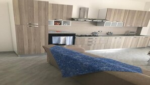A modern kitchen with wooden cabinets, a gas stove, and a built-in oven. - Casa Antonella Nice apartment (Capo Rizzuto)