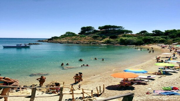 A beach with clear water, people swimming, and a boat in the distance. - Casa Antonella Nice apartment (Capo Rizzuto)
