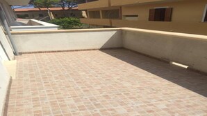 A rooftop patio with a tiled floor, a small garden area, and a view of neighboring buildings. - Casa Antonella Nice apartment (Capo Rizzuto)