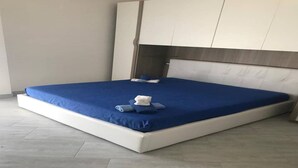 A modern bedroom with a large bed, a headboard, and a wardrobe. - Casa Antonella Nice apartment (Capo Rizzuto)
