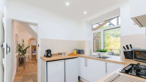 Eine moderne Küche mit weißen Schränken, einem eingebauten Ofen, einer Spüle und einem Fenster mit Blick auf einen Garten.