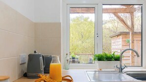 Eine Küche mit Wasserkocher, einem Glas Orangensaft und einem Croissant auf der Arbeitsfläche.