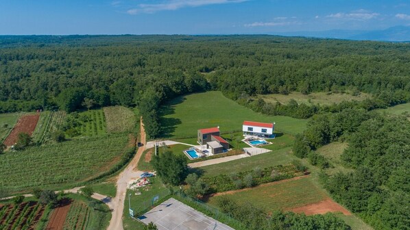 Una casa grande con piscina, rodeada de un paisaje boscoso.