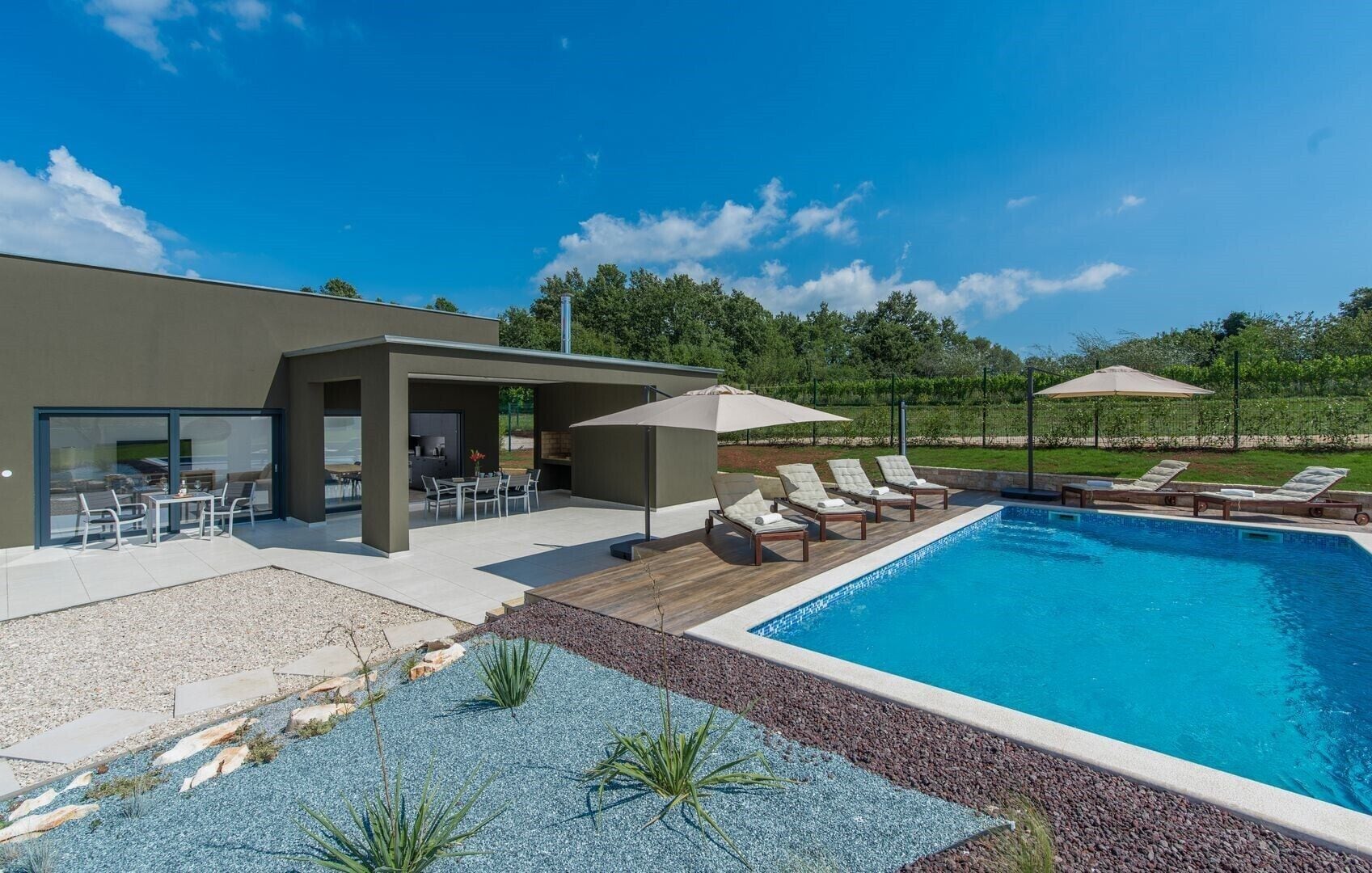 Uma área moderna com piscina ao ar livre, cadeiras de sol, churrasqueira e um espaço coberto para relaxar.