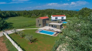 A modern two-story house with a swimming pool, surrounded by a well-maintained lawn and trees. - Luxury villa Sorella in Istria, private pool (Barban)