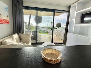 A modern living room with a sofa, a table, and a large sliding glass door leading to an outdoor patio area.