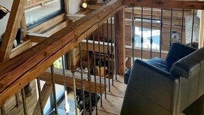 A wooden interior with a staircase, a sofa, and a view of a wooden deck outside. - Schönbacher Hof with a view of the Hohe Salve (Hopfgarten im Brixental)