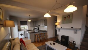 Un espacio habitable compacto con cocina, sofá, mesa de centro y chimenea.