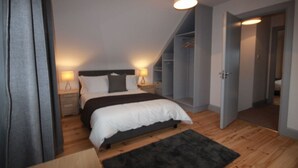 Et soveværelse med seng, natborde, et garderobeskab og en loftlampe.