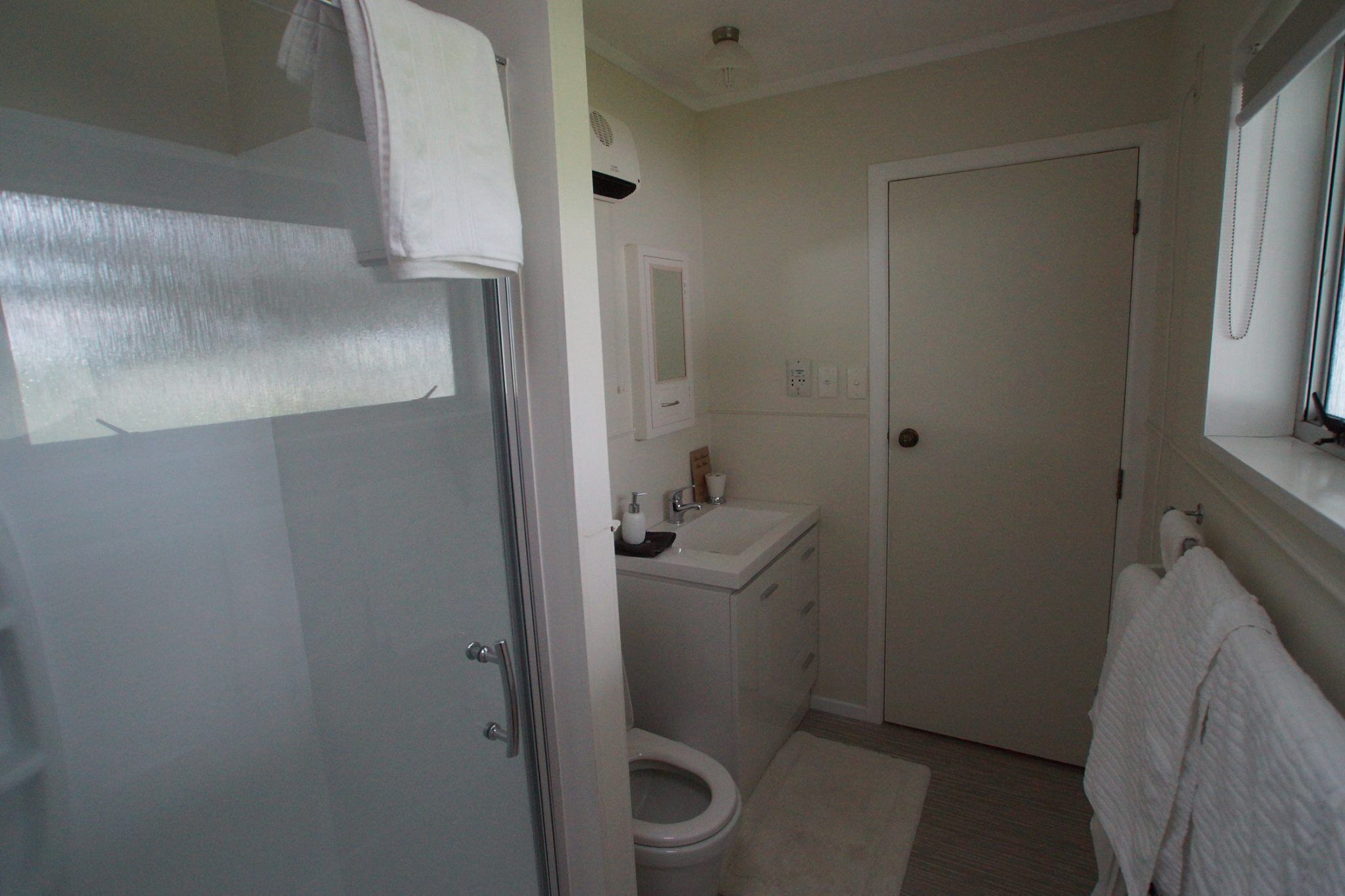 A small, white bathroom with a toilet, sink, and mirror.