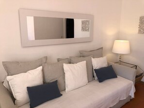 Relax in a serene space with a neutral-toned sofa, large mirror, and modern floor lamp.