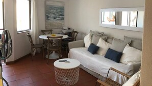 Una sala de estar con un sofá, una mesa de comedor, sillas, una mesita redonda y un ventilador de techo.