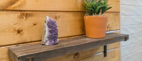 Eine Holzbank mit einem violetten Kristall und einem Topfpflanzen vor einer Holzwand.