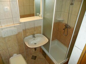 Ein Badezimmer mit Waschbecken, Spiegel, Toilette und Dusche.