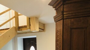 A spacious room with a wooden staircase, a dark wooden door, and a large wooden cabinet. - Marschenhof at the lakes. (Xanten)