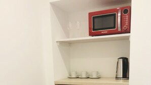 A compact kitchenette with a red refrigerator, a microwave, and a coffee maker on a shelf. - Marschenhof at the lakes. (Xanten)