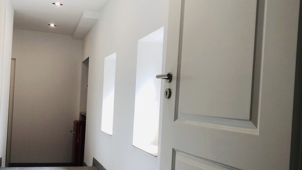 A hallway with a tiled floor, white walls, and a door with a keyhole. - Marschenhof at the lakes. (Xanten)