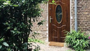 A brick wall with a wooden door featuring an oval window. - Marschenhof at the lakes. (Xanten)