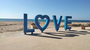 Large blue letters spelling "LOVE" on a beach with a clear sky. - Window to the Sea by Alexander 1p (Balestrate)