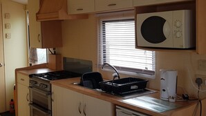 Une cuisine compacte équipée d’un four à micro-ondes, d’une cuisinière, d’un four et d’un évier.