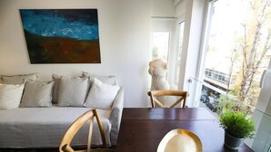 Una sala de estar moderna con un sofá, una mesa de comedor y un ventanal con vistas a la calle.