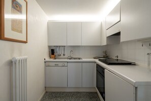 A compact kitchen with white cabinets, a dishwasher, and a stove.