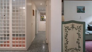 A hallway with a frosted glass partition, a wooden door frame with a floral design, and a painting on the wall. - Garden Apartment (Venice)