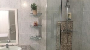 Une salle de bain avec une douche à parois de verre, un lavabo en marbre et un miroir.